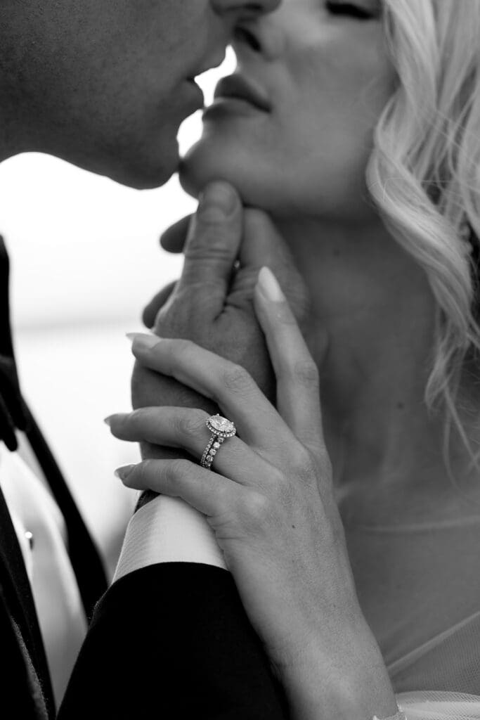 Black and white photo, closeup of brides ring during ceremony kiss