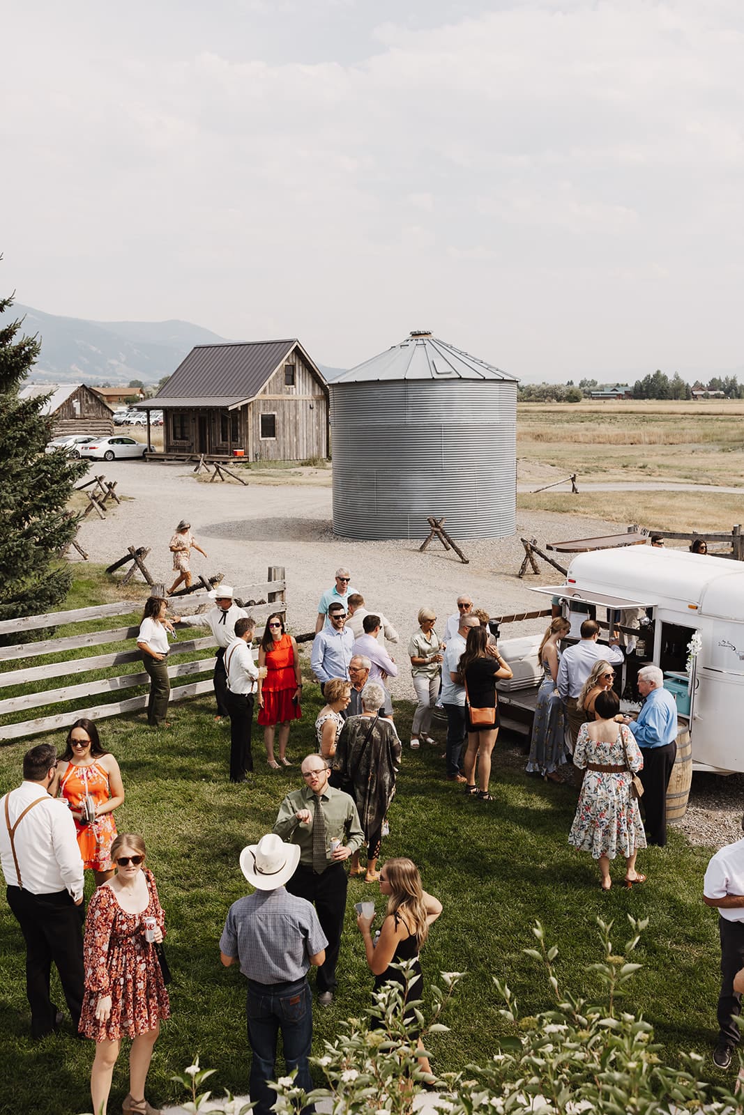 Guests gathered in the grass, enjoying pre-ceremony cocktails at a bozeman, summer wedding. 