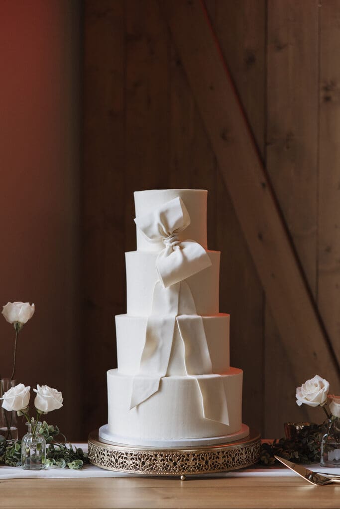 Elegant wedding cake at The White Raven venue near Missoula, Montana, featuring rustic wooden chairs, modern decor, and romantic floral details captured by Missoula wedding photographer Frazier & Co.