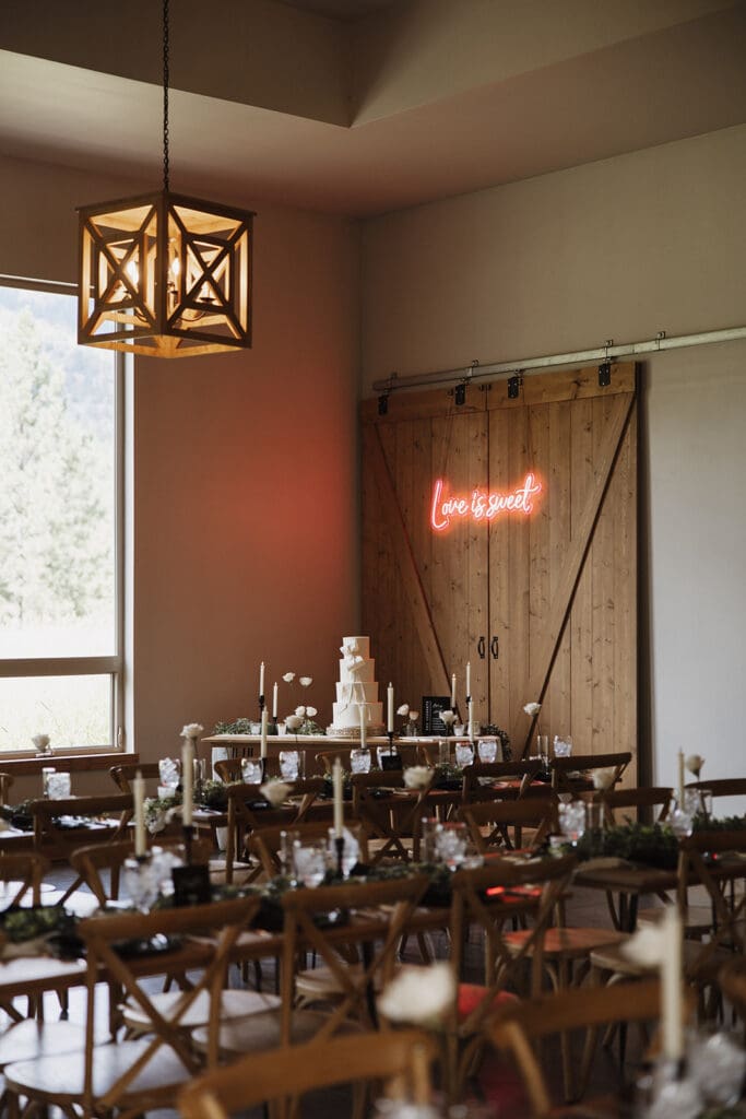 Elegant wedding reception setup at The White Raven venue near Missoula, Montana, featuring rustic wooden chairs, modern decor, and romantic floral details captured by Missoula wedding photographer Frazier & Co.