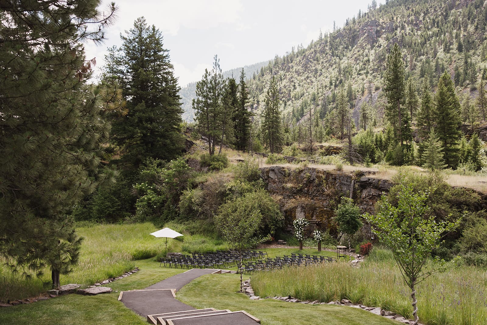 Scenic exterior view of The White Raven wedding venue near Missoula, Montana, surrounded by lush pine trees and mountain backdrops, perfect for summer weddings.
