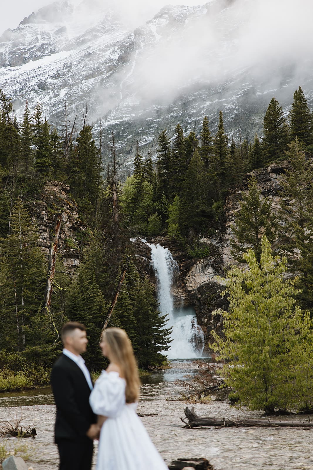 Bride and groom standing in front of a waterfall in GNP during their elopement
