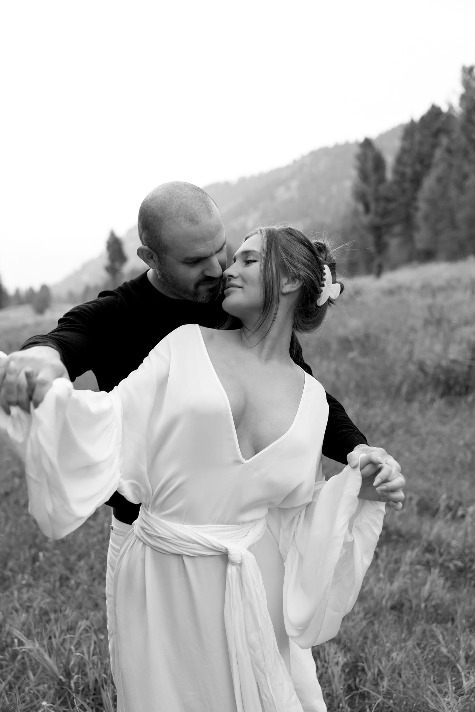 Couple sharing an intimate laugh while walking through a meadow in Big Sky.