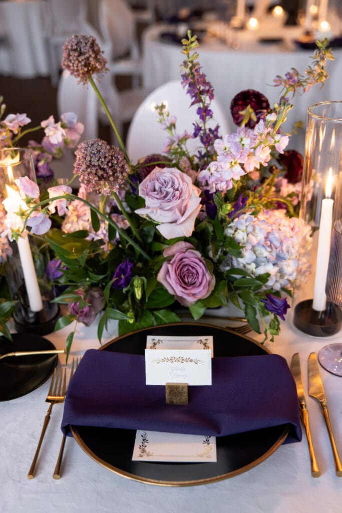 Editorial place setting with purple napkin, name card, and floral arrangement at a Biltmore Estate wedding reception.