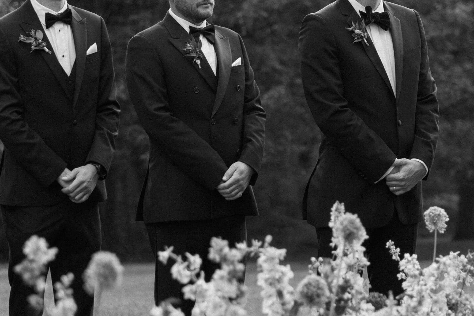 Groomsmen in black tuxedos standing at the ceremony on the Diana Lawn, photographed by a Biltmore wedding photographer.