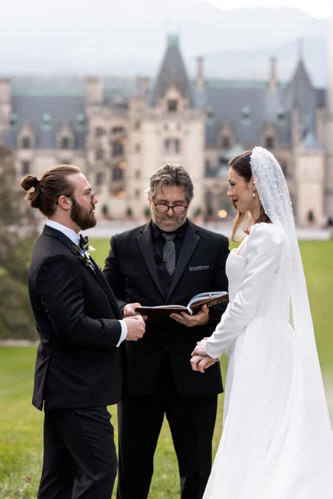 Wedding ceremony on the Diana Lawn at the Biltmore Estate with a floral arch and full wedding party, photographed by a Biltmore wedding photographer.
