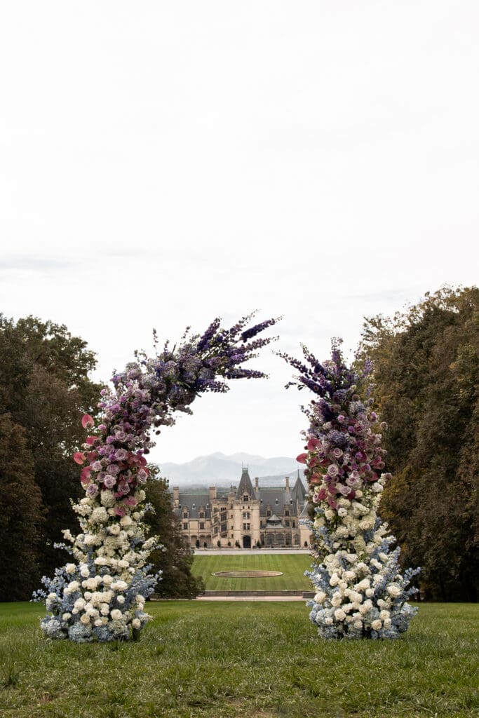 Luxury floral ceremony arch on the Diana Lawn with the Biltmore Estate in the background, part of editorial Biltmore wedding photos by a Biltmore wedding photographer.
