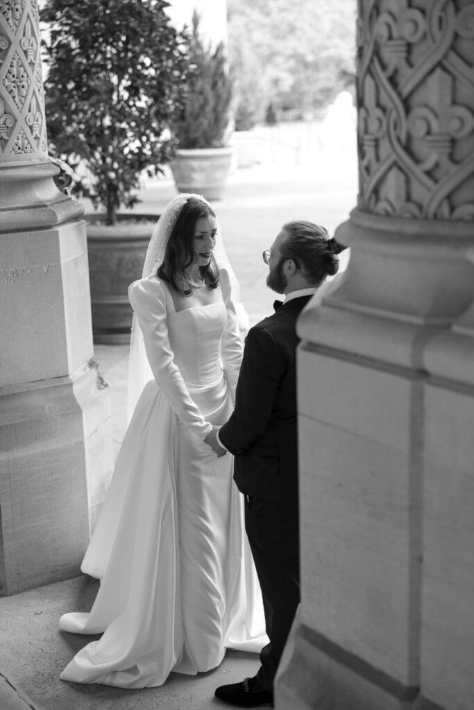 Black-and-white photo of the bride and groom walking together at the Biltmore Estate.