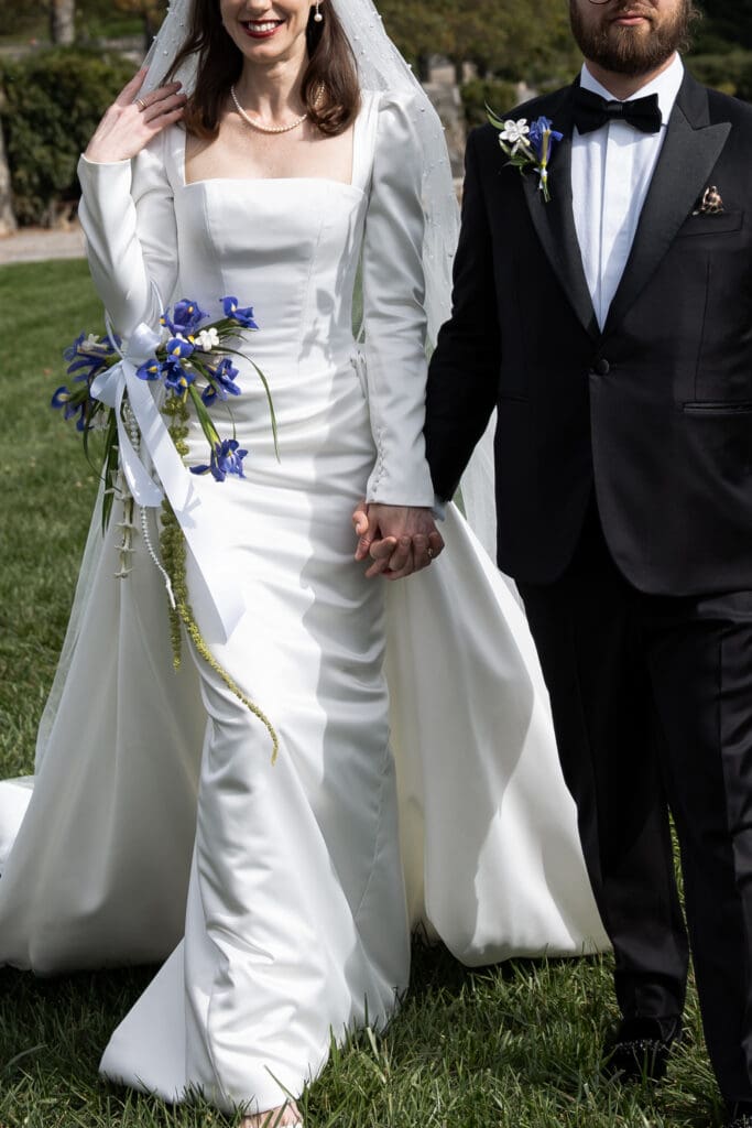 Bride holding a purple bouquet while walking hand-in-hand with the groom at the Biltmore Estate.