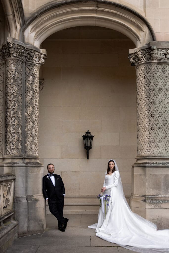 Bride and groom standing beneath an ornate stone archway at the Biltmore Estate, photographed by a Biltmore wedding photographer.