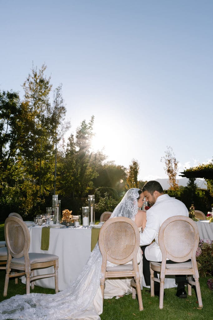 Bride and groom seated at outdoor reception table during golden hour at Oceana’s Gardens in Boulder.