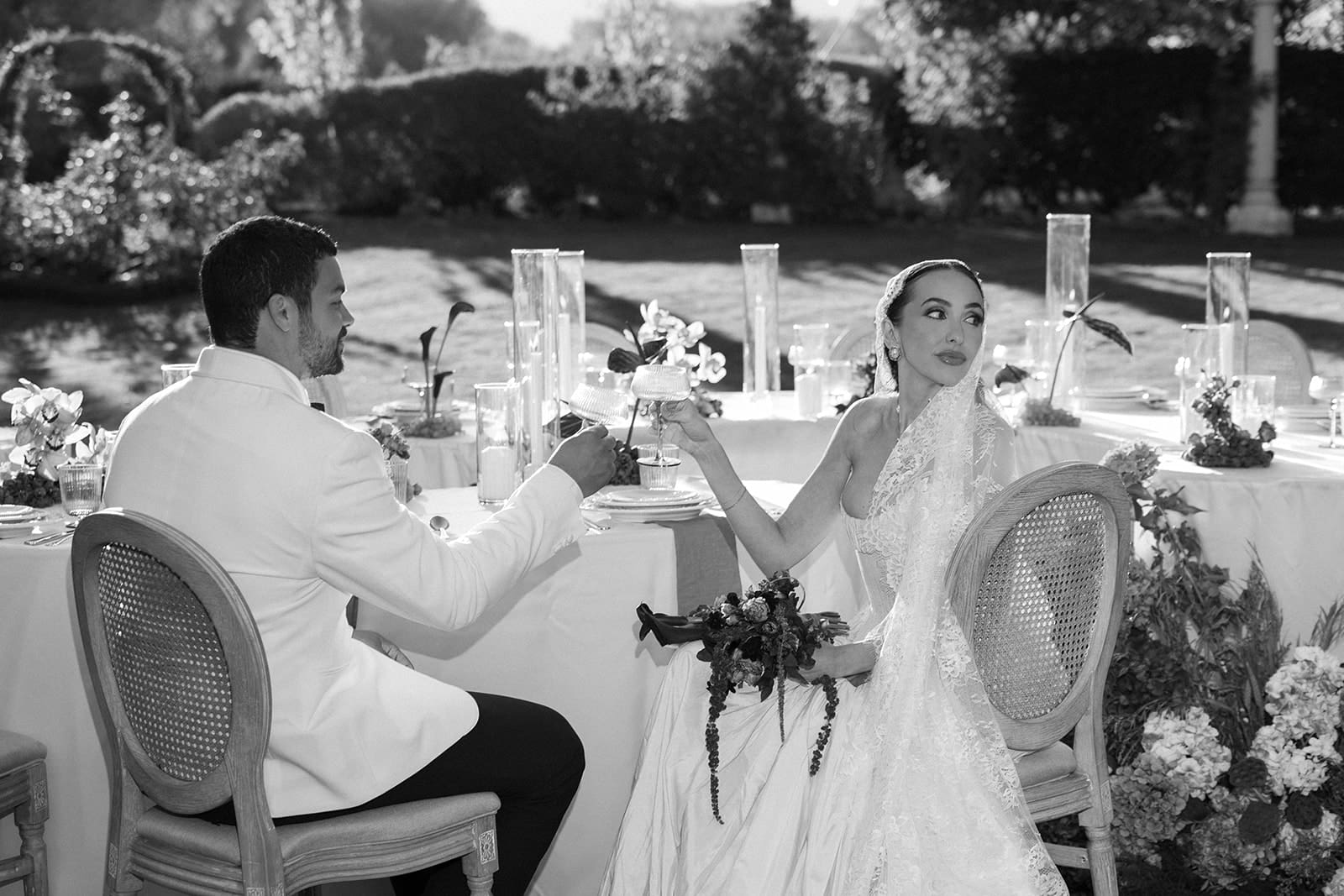 Black and white photo of couple toasting at outdoor reception at Oceana’s Gardens.