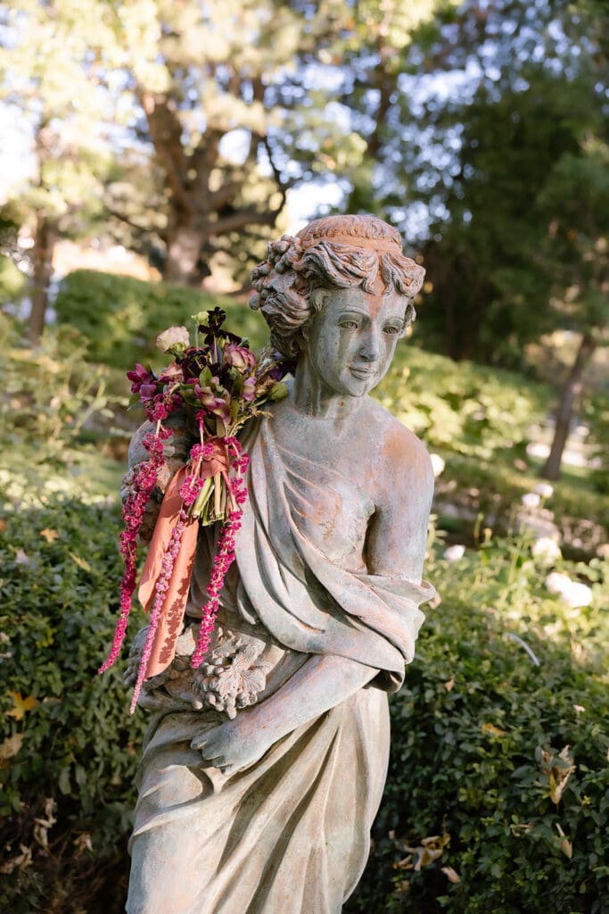 Classical garden statue styled with cascading florals at Oceana’s Gardens wedding.