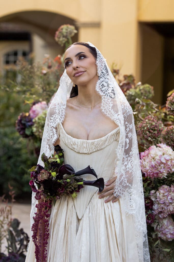 Bride holding dramatic bouquet in front of floral installation at Oceana’s Gardens.
