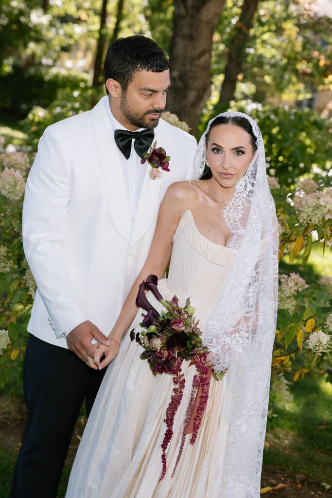 Bride and groom in editorial portrait holding cascade bouquet at Oceana’s Gardens in Boulder.