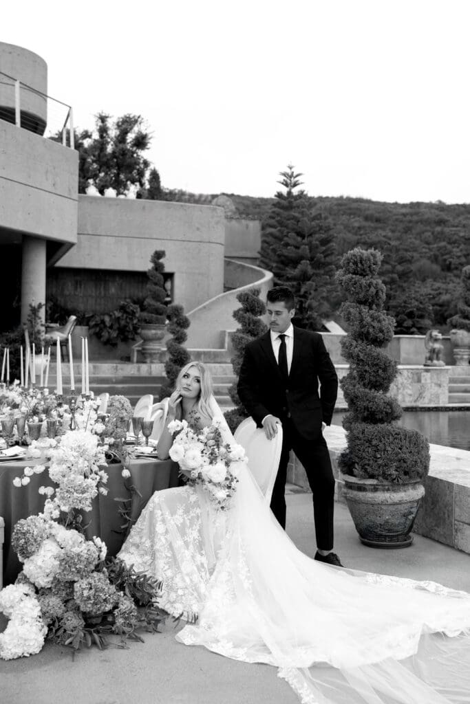 Black and white editorial wedding portrait of a couple seated at a floral tablescape at Stone Mountain Estate, photographed by Malibu CA wedding photographer Frazier & Co.