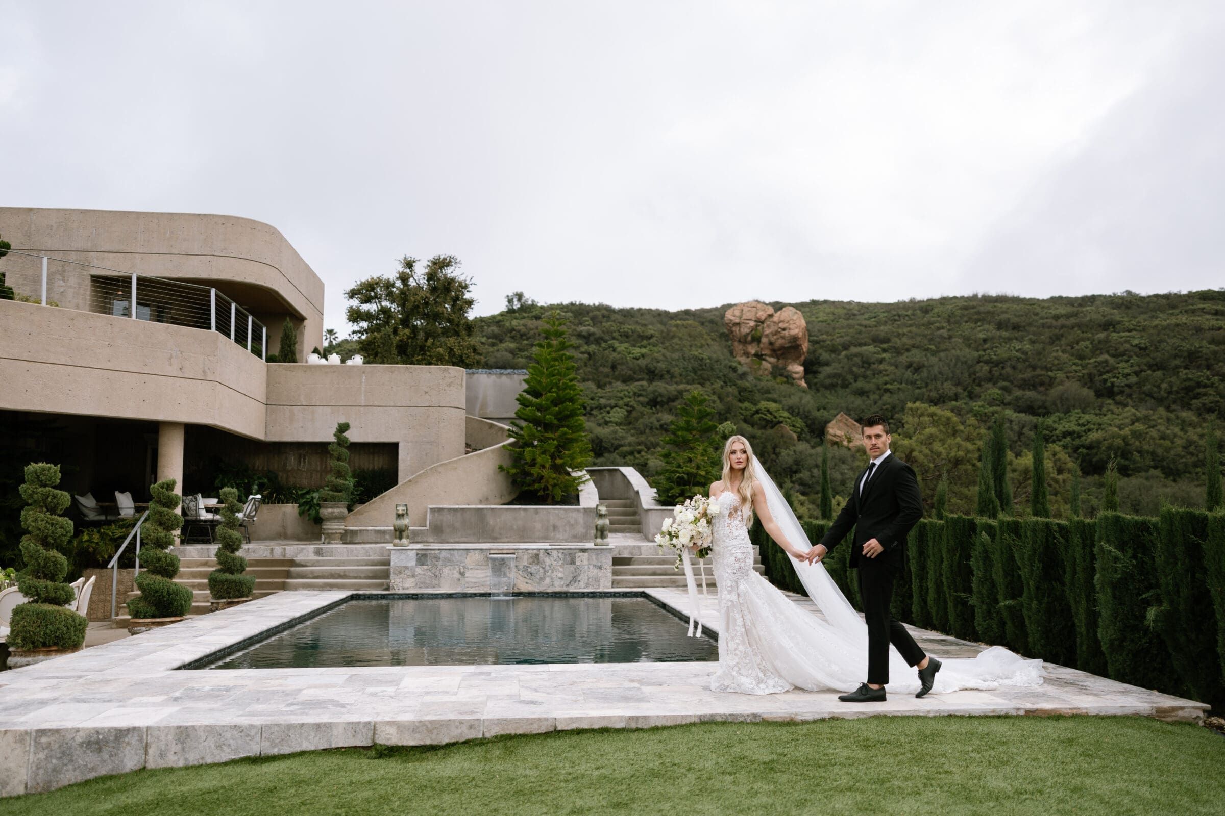Bride and groom walking along the pool at Stone Mountain Estate with panoramic mountain views, photographed by luxury Malibu CA wedding photographer Frazier & Co.