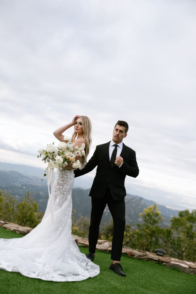 Elegant bride and groom standing on the hilltop lawn at Stone Mountain Estate with sweeping Malibu mountain views, photographed by a Malibu CA wedding photographer.