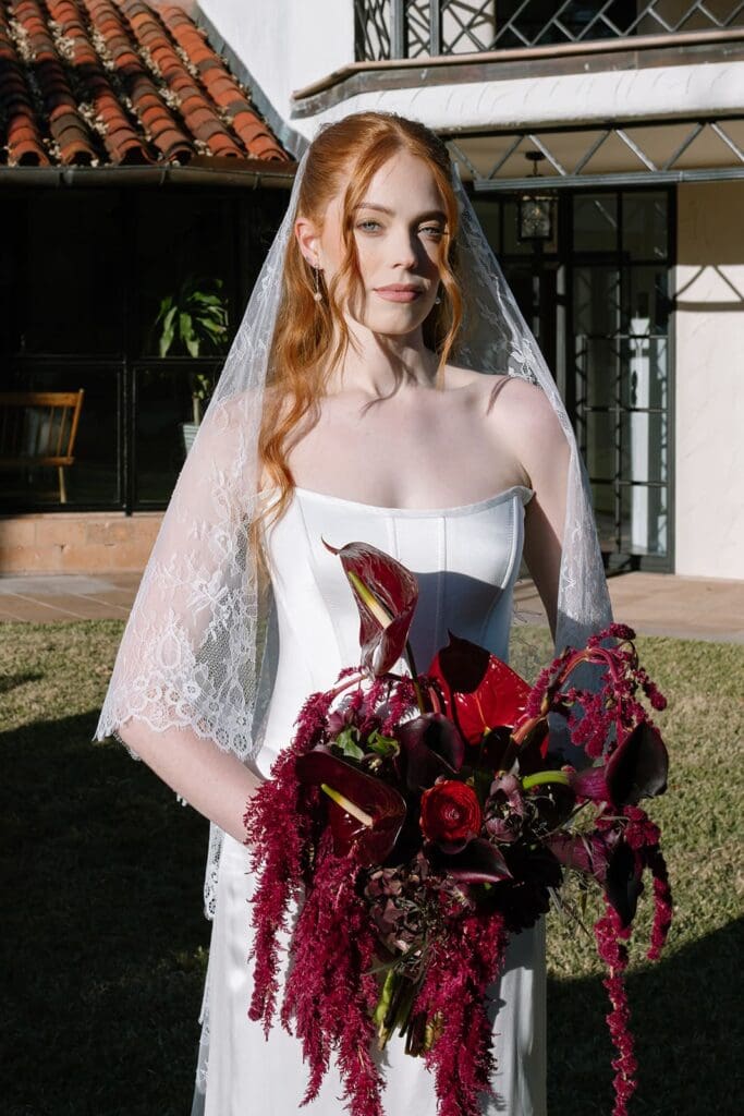 Bride holding dramatic, luxury burgundy bouquet during outdoor editorial wedding portrait in Santa Barbara.