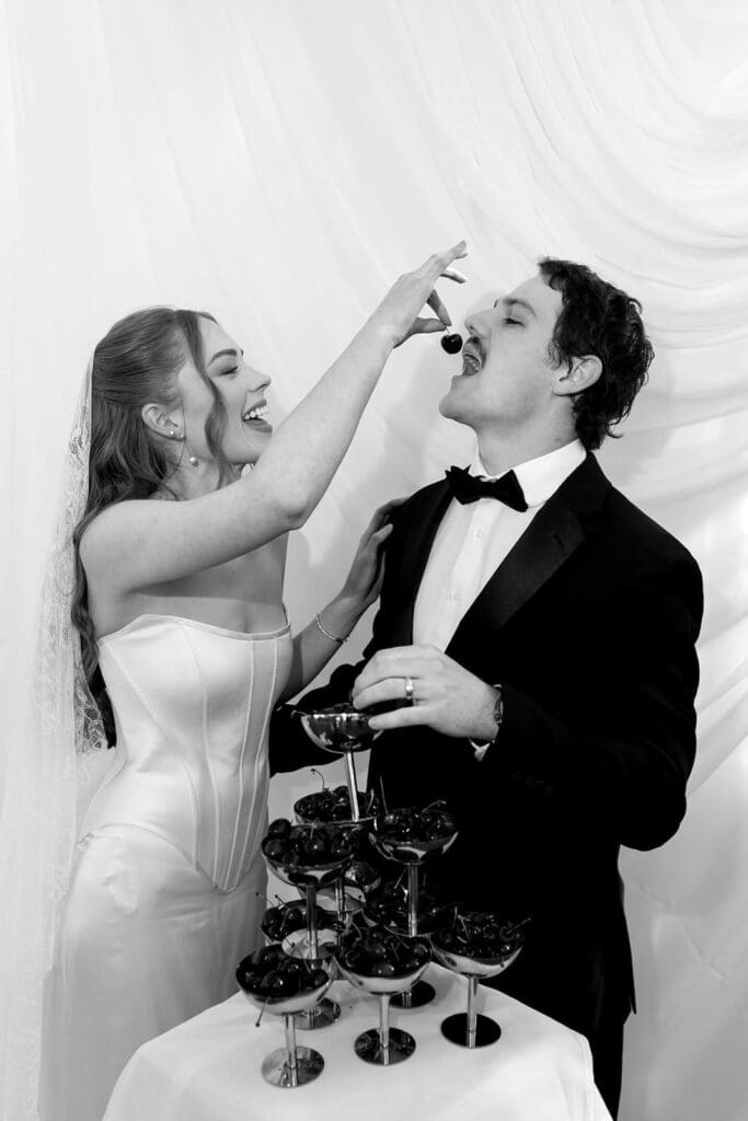 Black and white editorial wedding photo of couple sharing champagne tower moment at Santa Barbara destination wedding.