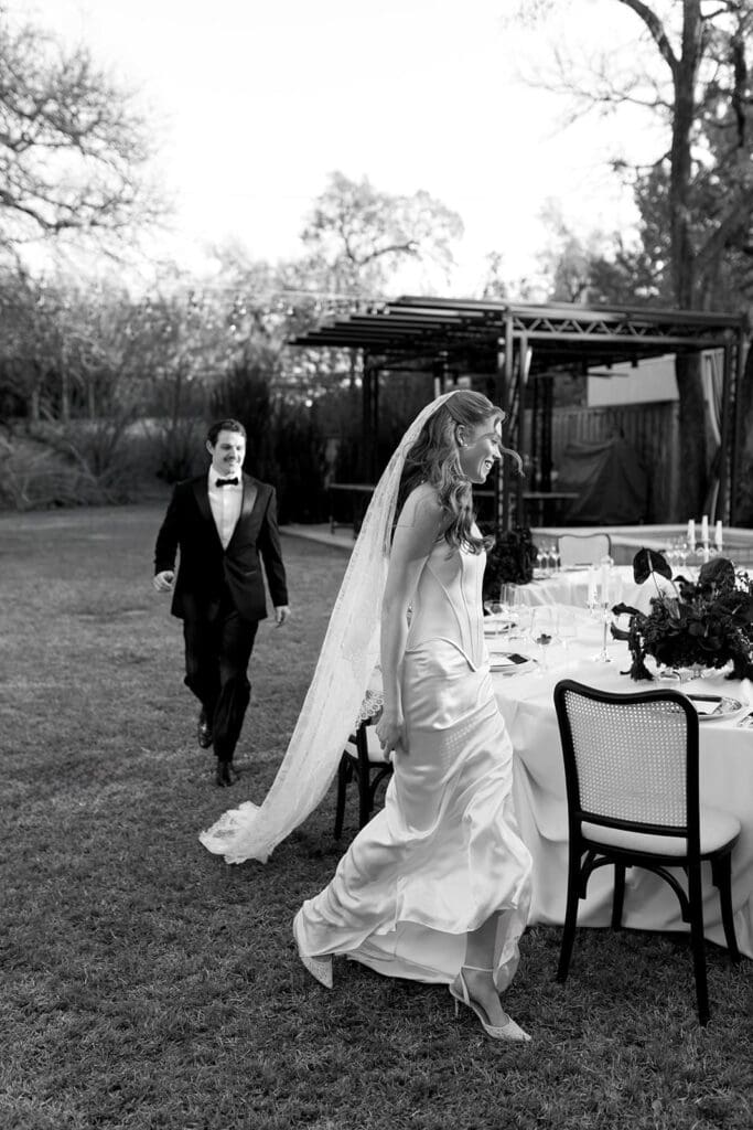 Black and white photo of bride walking through outdoor wedding reception at Santa Barbara estate.