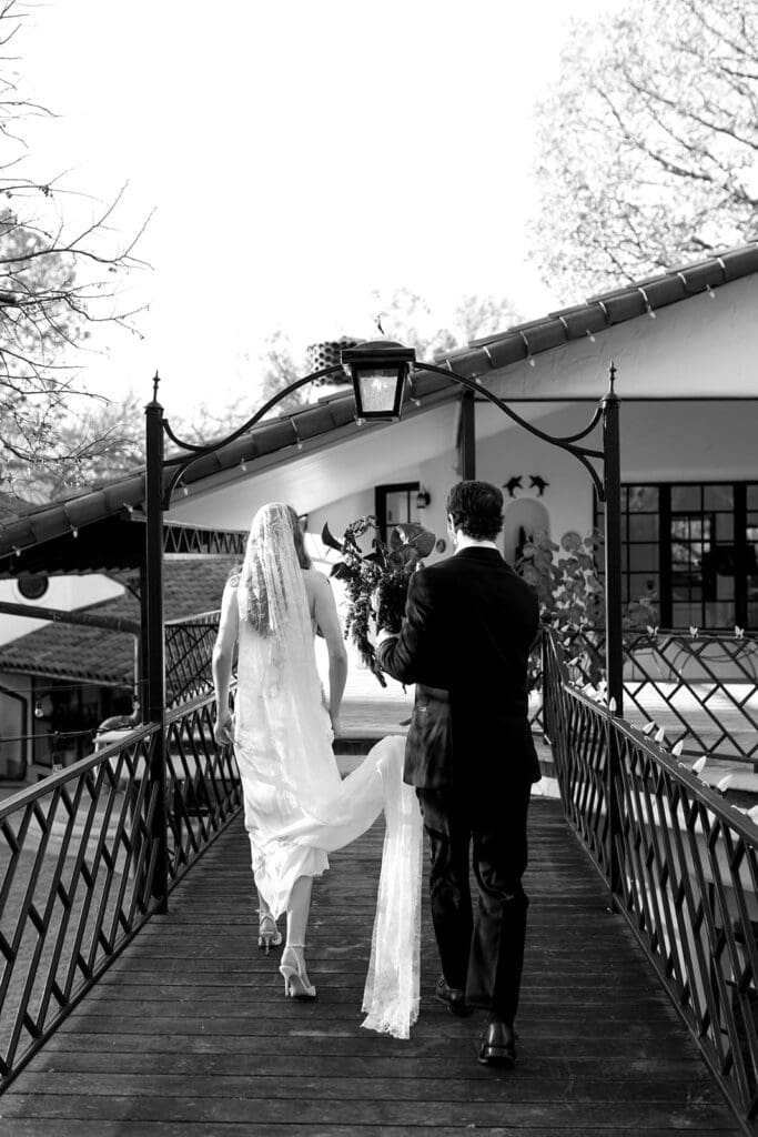 A cinematic black-and-white moment captured by Santa Barbara Editorial Destination Wedding Photographer Frazier & Co., featuring a couple walking through a timeless California estate. Outdoor venues in Santa Barbara offer refined architecture and natural light—perfect for couples seeking editorial storytelling at California wedding venues outdoor.