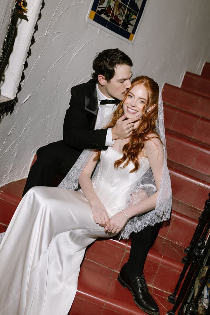 Editorial wedding couple seated on historic staircase in Santa Barbara estate, captured in refined destination wedding style.