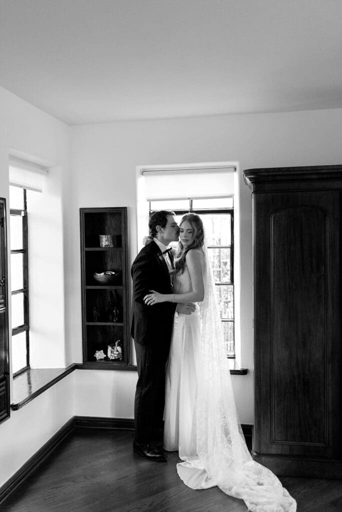 Black and white editorial wedding couple embracing indoors at Santa Barbara estate venue.