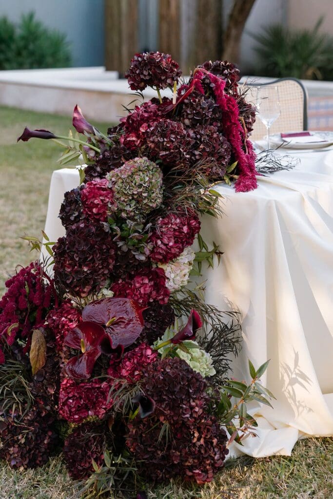 Editorial wedding floral installation cascading over reception table at outdoor California estate.