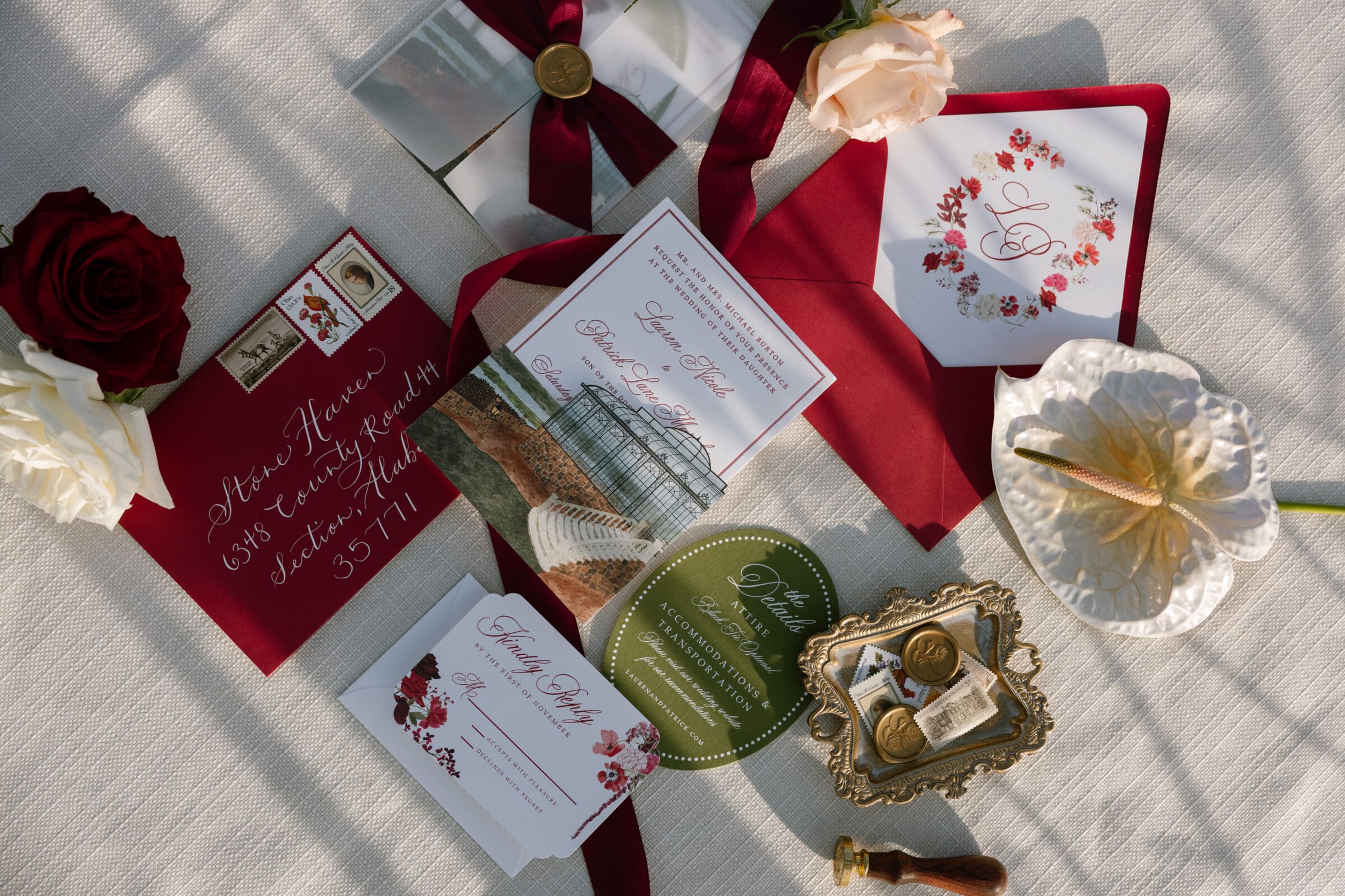 Luxury wedding invitation suite with burgundy envelopes, wax seals, floral monogram, and vintage stamps photographed at Stone Haven wedding venue in Alabama.