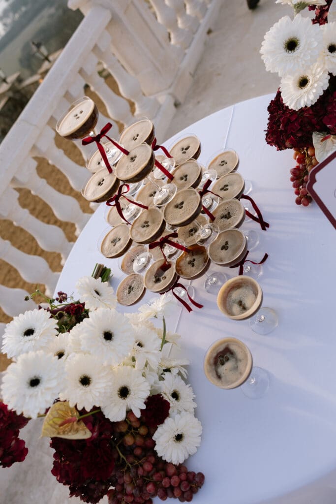 Luxury espresso martini tower tied with burgundy silk bows and surrounded by florals on the terrace at Stone Haven wedding venue in Alabama.