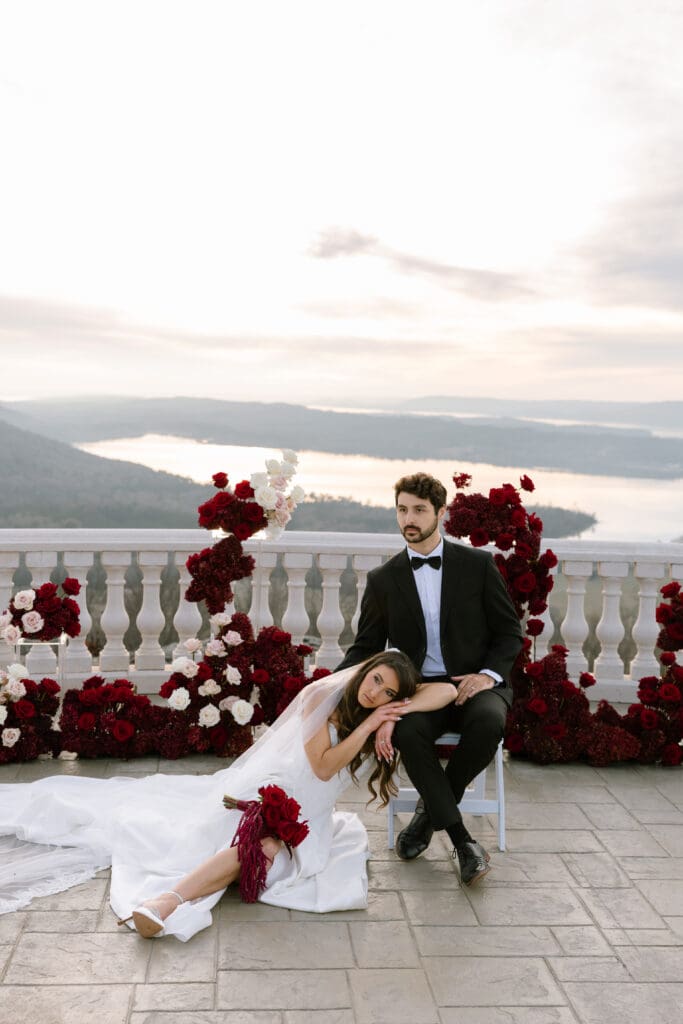 Editorial bridal portrait of bride resting beside groom with deep red bouquet at Stone Haven wedding venue in Alabama, styled for a luxury wedding photographer editorial.