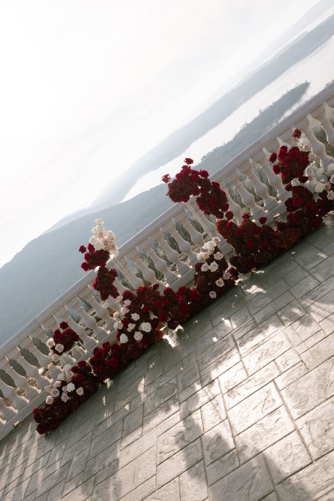 Romantic red and ivory floral ceremony installation on the terrace overlooking mountains at Stone Haven wedding venue in Alabama, styled for an editorial wedding setting.