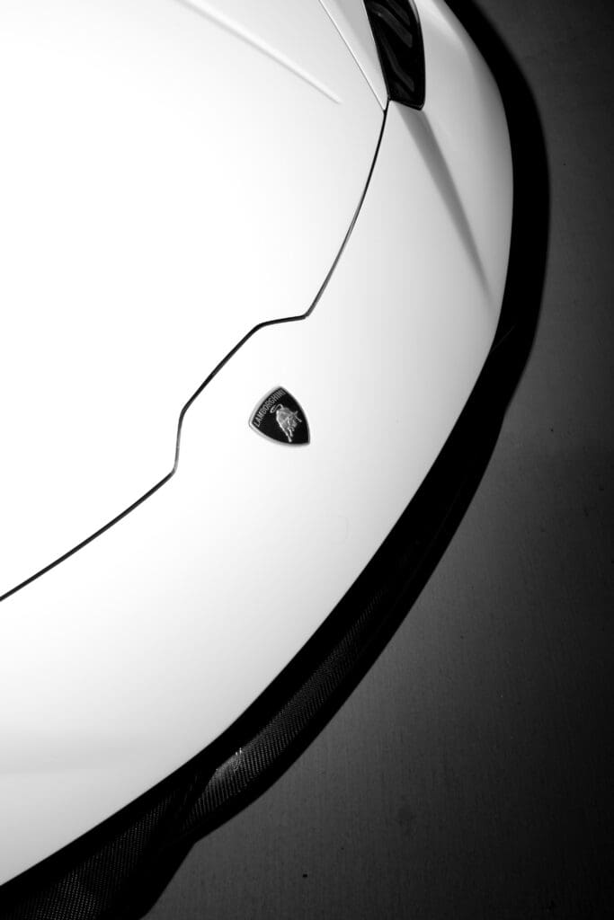 Minimalist black and white close-up of the Lamborghini emblem on a white luxury supercar used for an editorial wedding shoot at Stone Haven wedding venue in Alabama.