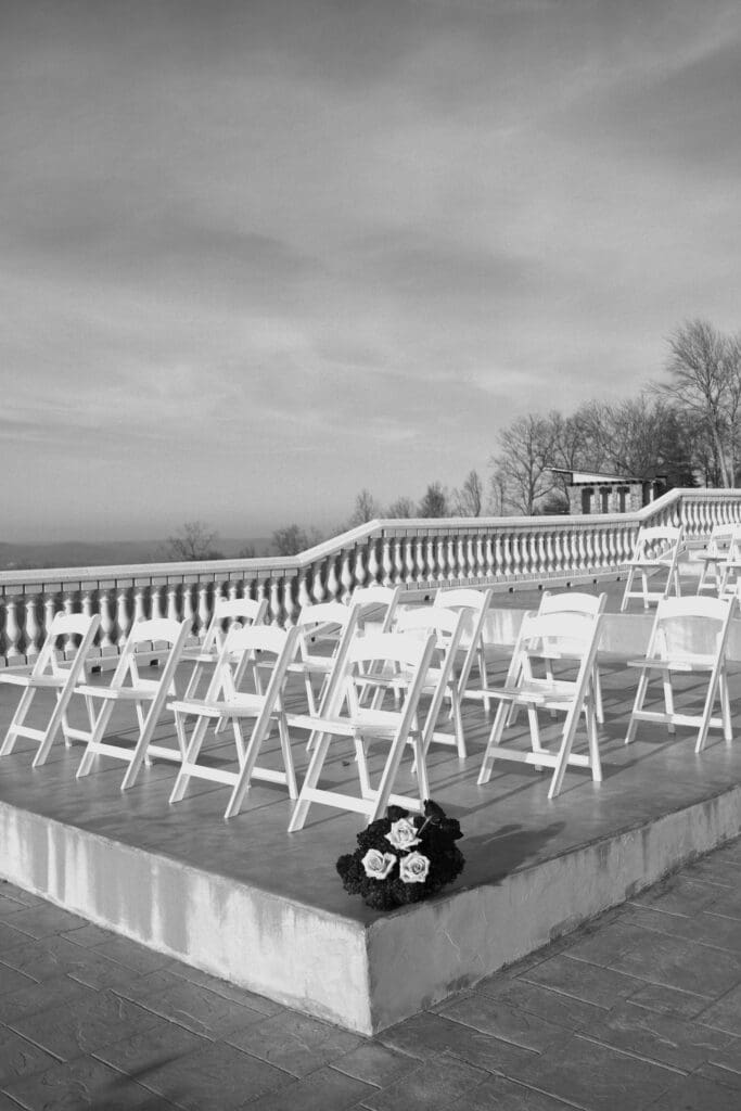 Black and white photo of white ceremony chairs arranged on the elevated stone terrace at Stone Haven wedding venue in Alabama overlooking the surrounding landscape.