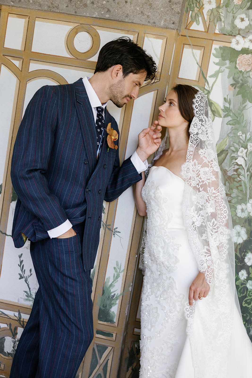 Groom and bride intimate moment in classical Rome venue with botanical wallpaper, editorial wedding photography at Relais Appia Antica