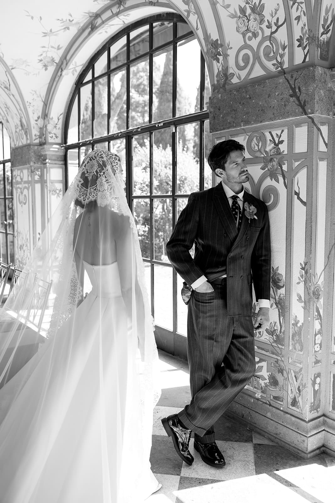 Black and white silhouette of bride and groom in classical doorway with flowing veil, romantic editorial wedding photography in Rome