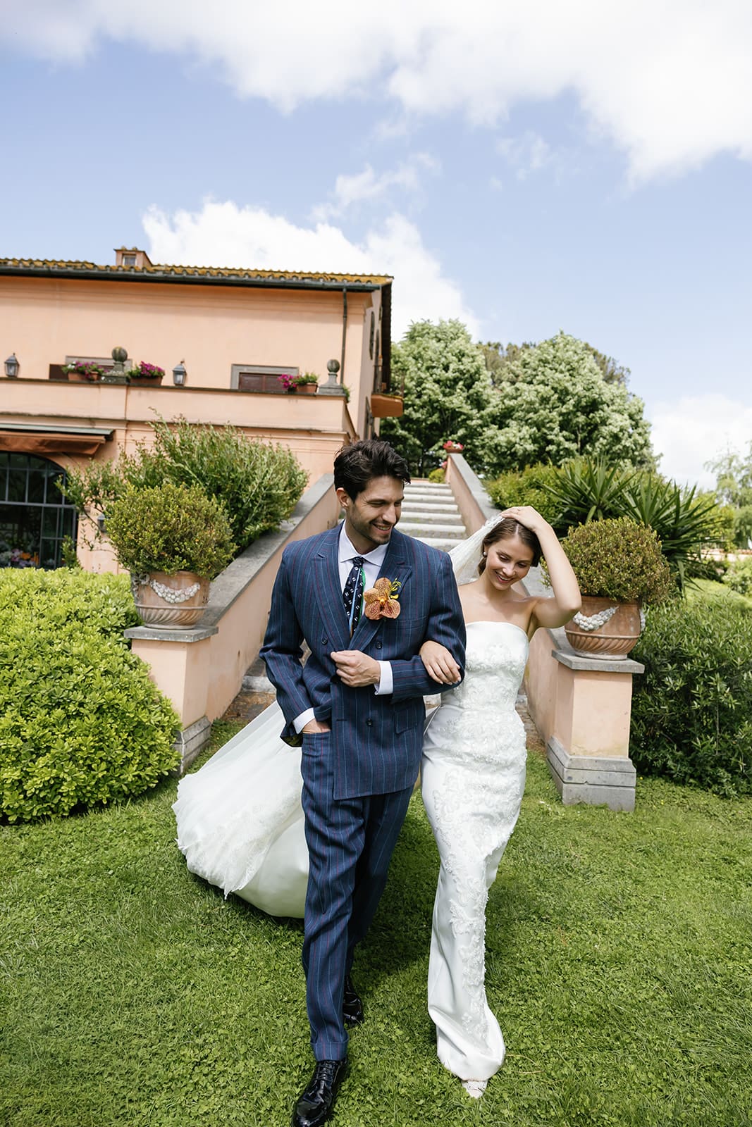 Bride and groom walking through manicured villa grounds at Relais Appia Antica, couple moment at luxury Rome destination wedding with classical estate backdrop