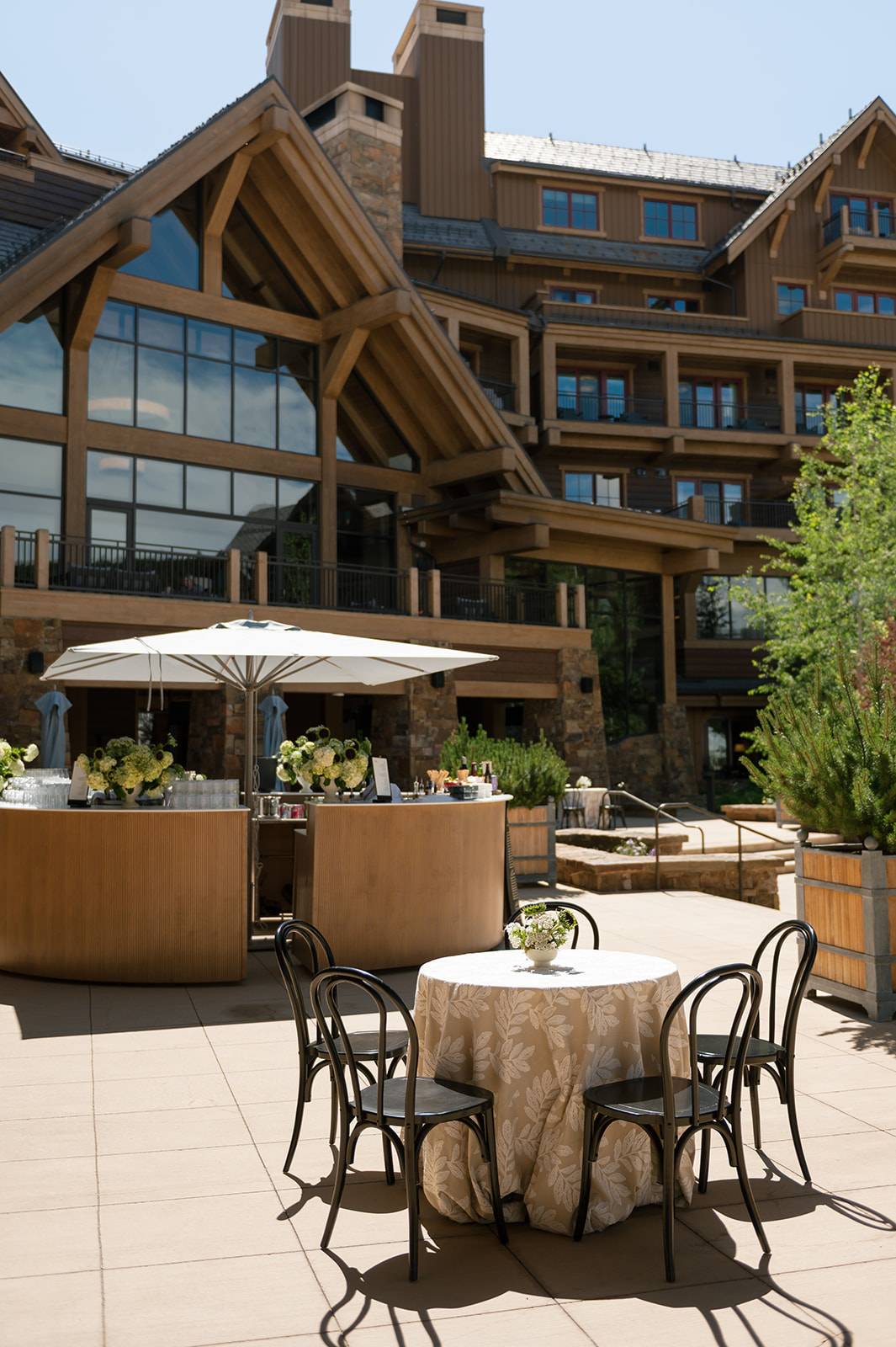 Timber and stone exterior of Montage Big Sky with outdoor lounge seating and umbrella-shaded tables
