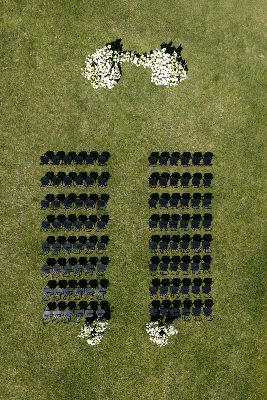 Aerial view of wedding ceremony seating at Montage Big Sky Montana with black chairs and white floral aisle markers on the Grand Lawn