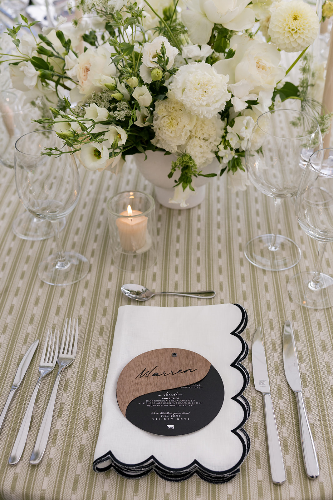 Wedding reception place setting with white floral centerpiece, scalloped linen napkin, and place card at Montage Big Sky