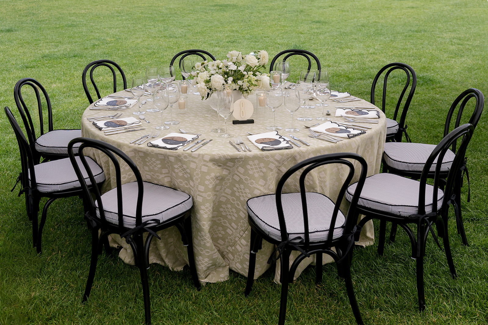 Round reception table with sage linen and white floral centerpiece set on the lawn at a Montage Big Sky Montana wedding