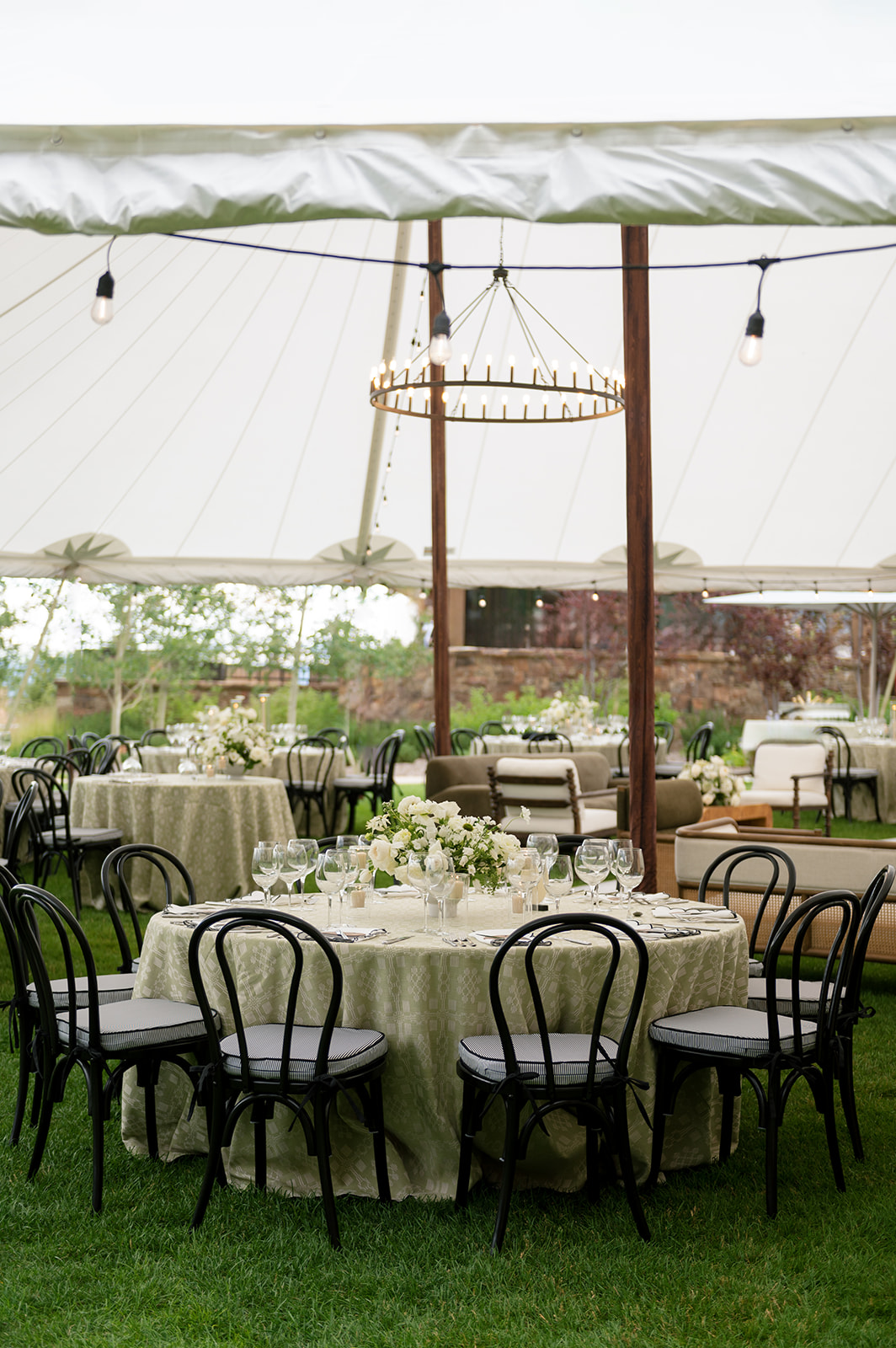 Sailcloth reception tent at Montage Big Sky with round tables, string lights, and a wagon-wheel chandelier