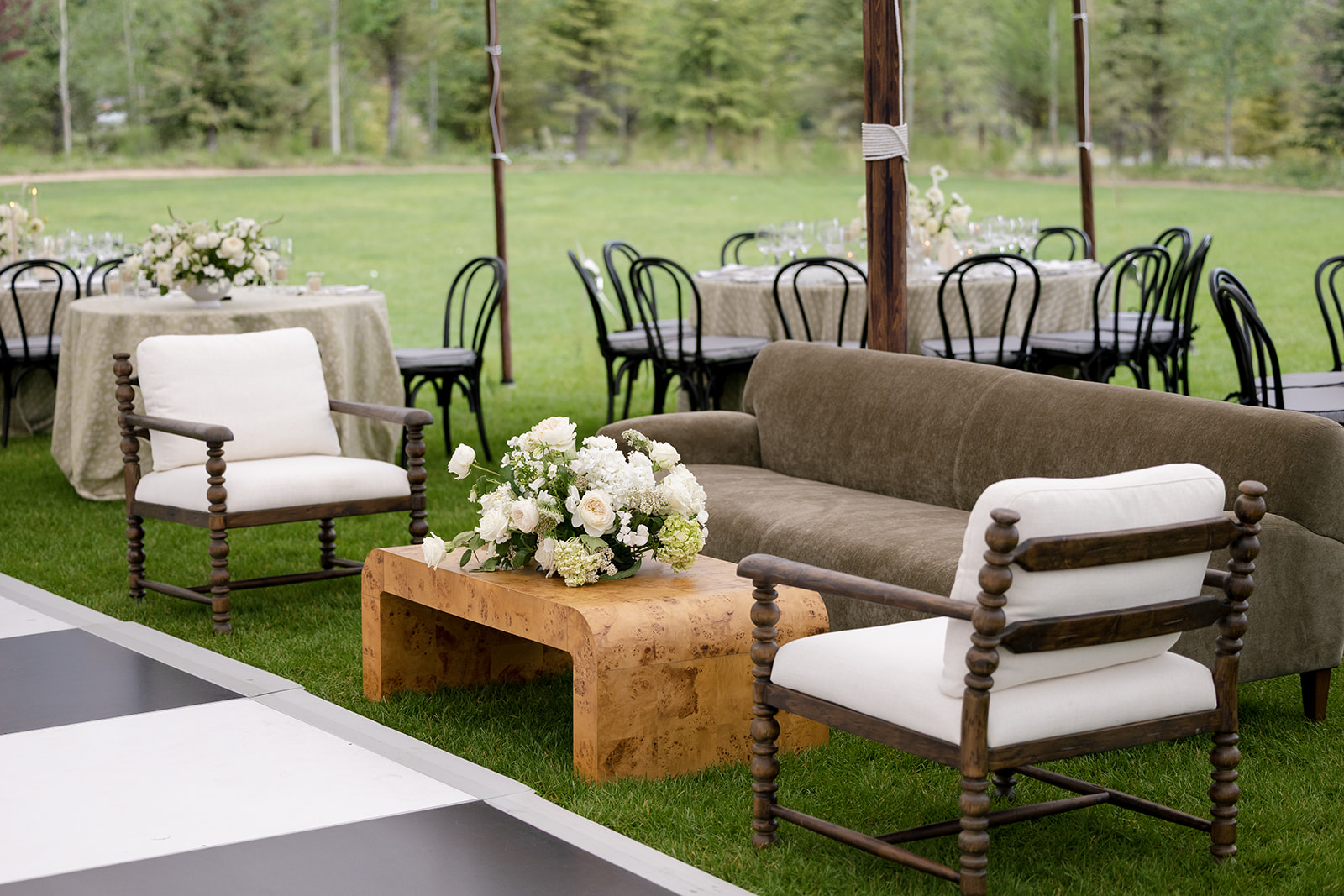 Outdoor lounge area with sage sofa and boucle chairs beside a black and white checkered dance floor at Montage Big Sky