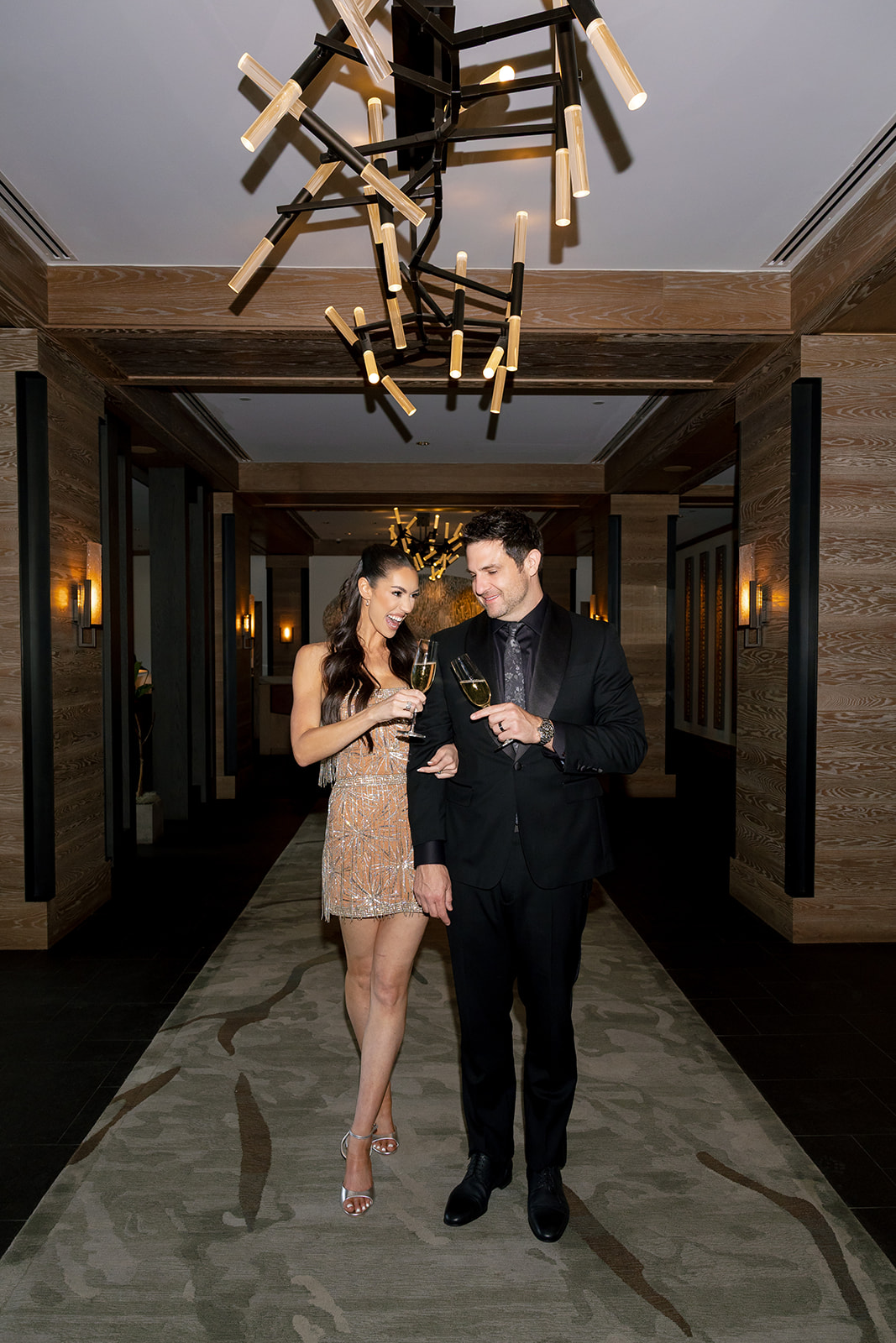 Bride and groom walking a hallway at the Montage in Big Sky, Montana, bride in a gold fringe reception dress