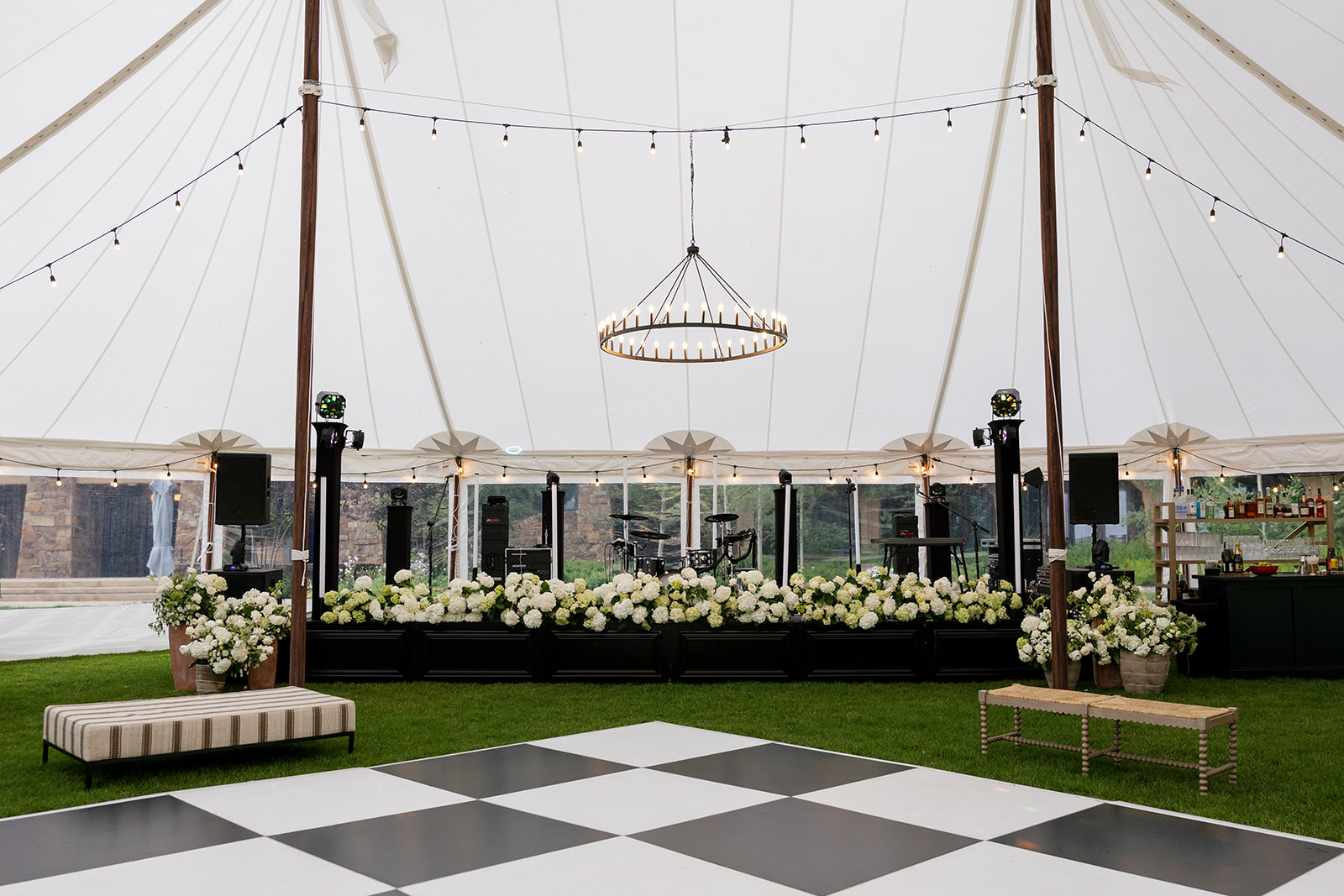 String-lit reception tent with checkered dance floor and floral-lined stage at Montage Big Sky