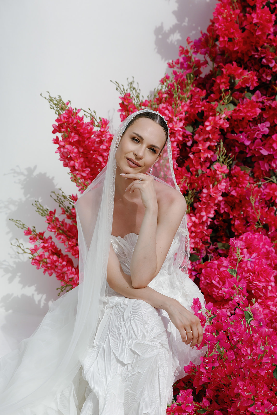 Editorial bridal portrait framed by vibrant pink floral installations at a Kalesma Mykonos wedding in Greece.