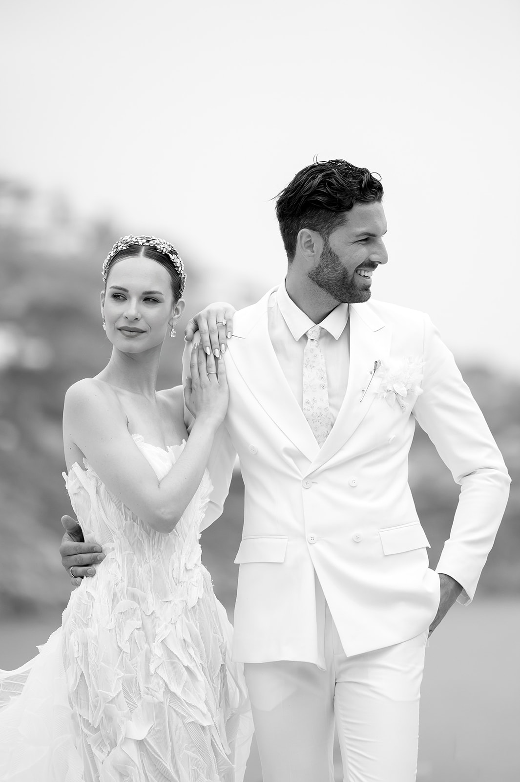 Black and white portrait of a bride and groom walking together in elegant wedding attire at Kalesma Mykonos.
