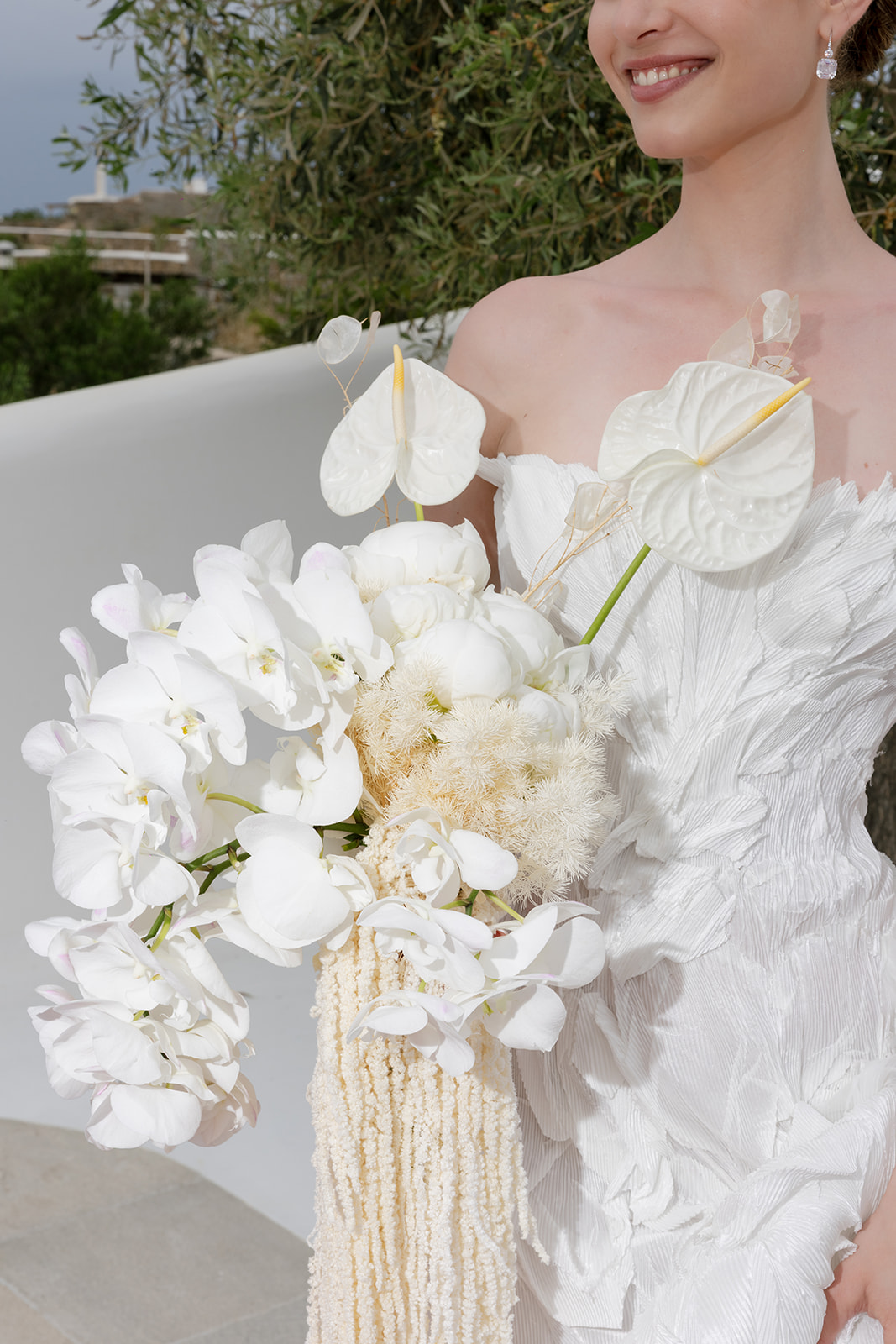 Close up of sculptural white bridal florals and delicate wedding dress details at an editorial Mykonos wedding.